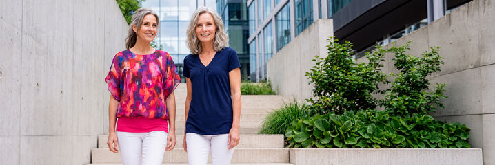 Zwei Frauen stehen l&auml;chelnd auf einer Treppe im Freien
