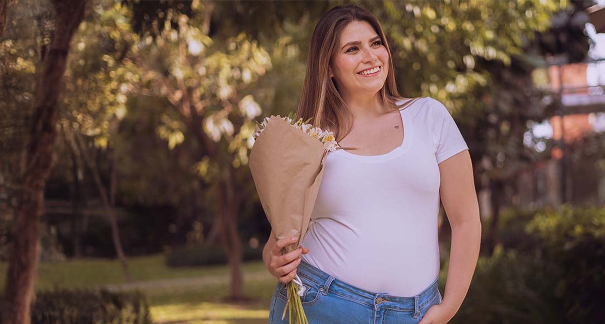 Dame in weißem T-Shirt mit Blumen in der Hand